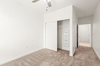 An empty bedroom with white walls and a ceiling fan
