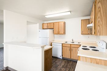 An empty kitchen with white appliances and wooden cabinets
