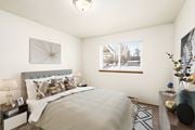 Post Falls apartment for rent - A bedroom with white walls, a large window on the back wall, and staged with a queen size bed, side tables, a dresser, and a rug.at Clearwater, Post Falls