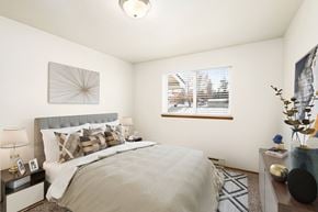 Post Falls apartment for rent - A bedroom with white walls, a large window on the back wall, and staged with a queen size bed, side tables, a dresser, and a rug.at Clearwater, Post Falls