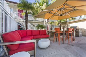 San Diego apartment for rent - Outdoor resident lounge with a red patio sofa, high table with orange chairs next to the pool, with a gas BBQ at Pacific Sands, San Diego, California