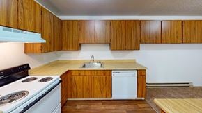 Renton apartment for rent - Well-equipped kitchen at Heritage Grove Apartments in Renton WA, with wood-grain cabinetry, full-size refrigerator, and modern finishes.