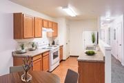 Lewiston apartment for rent - Bright kitchen with honey-colored cabinets and white appliances and faux wood flooring. You can also see down the hallway with white walls and taupe carpet.at Canyon View, Lewiston