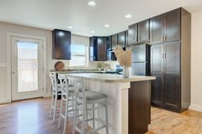 Bozeman townhouse for rent - a kitchen with a large island with bar stools and dark wood cabinets at Copper Pines, Bozeman, MT