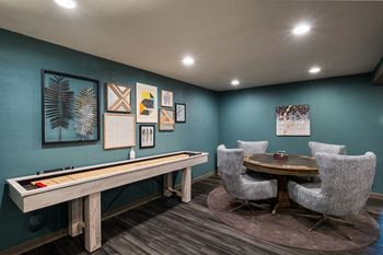 A game room with a shuffleboard table and chairs