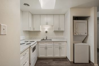A kitchen with white cabinets and white appliances and a washer and dryer