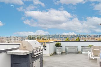 A roof deck with a barbecue grill and a view of the city