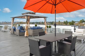 A rooftop patio with tables and chairs and an orange umbrella