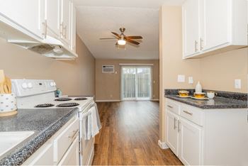 An empty kitchen with white cabinets and a ceiling fan
