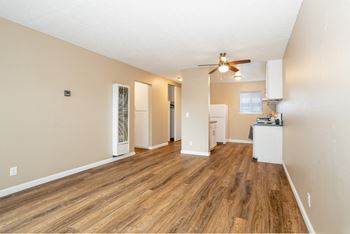 An empty living room with a ceiling fan and a kitchen