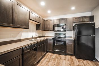 A kitchen with black appliances and wooden cabinets