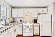 Olympia apartment for rent - L-shaped kitchen with white cabinets, a large window above the sink, and a white dishwasher, oven, stovetop, full-size fridge.at Capitol Crossing, Olympia, WA