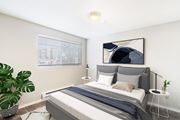 Olympia apartment for rent - Carpeted bedroom with white walls, a window on the left wall. Staged with a bed, side tables, and a houseplant.at Capitol Crossing, Washington