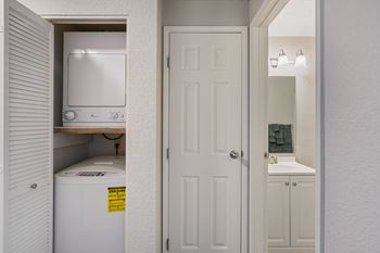 A white kitchen with a white door and a white refrigerator and sink