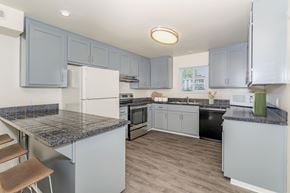 Chico apartment for rent - A kitchen with a granite counter top and grey cabinets at Gateway Student Apartments in Chico, CA.