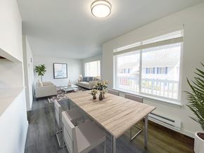 Snohomish apartment for rent - A dining room with white walls and a large sunny window that looks into the living room. Light-filled apartment staged with dining set and living room furniture.at The Trail, Snohomish, WA