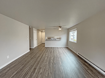 An empty living room with a ceiling fan and a window