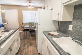Woodland apartment for rent - Galley kitchen with new white cabinets and gray faux granite countertops, with dining area visible in the distance at Woodland Village , California, 95695