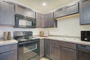 Bozeman apartment for rent - a kitchen with black appliances and wooden cabinets at Madison Park, Montana, 59718