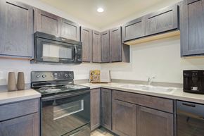 Bozeman apartment for rent - a kitchen with black appliances and wooden cabinets at Madison Park, Montana, 59718