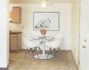 Post Falls apartment for rent - Dining area with ceiling fan, and the kitchen to the left. Staged with a table, 4 chairs, wall art, and flowers.at North Pointe, Post Falls Idaho