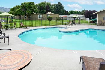 A resort style pool with chairs and tables and a fence around it