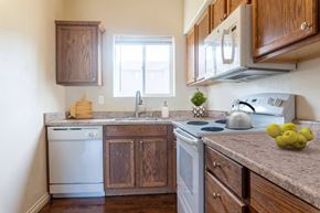 Kennewick apartment for rent - L-shaped kitchen with wood cabinets top and bottom, dishwasher, sink with window above, oven, stovetop, microwave. at Pine Tree Park, Washington, 99337