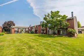 Fife apartment for rent - A large grassy area in front of a building with a tree in the foreground.