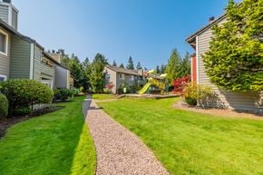 Mountlake Terrace apartment for rent - A playground with a slide is in the middle of a grassy area between two rows of houses.
