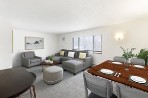 Billings apartment for rent - A modern living room with grey furniture and a wooden dining table at Rock Creek Apartments in Billings, MT.