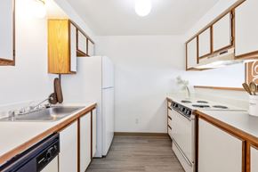 Billings apartment for rent - A double galley kitchen with white appliances and wooden cabinets at Shiloh Glen Apartments in Bilings.