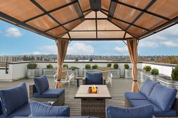 A roof terrace with blue couches and chairs and a fireplace