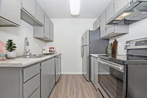 University Place apartment for rent - Kitchen with fridge, oven with cooktop, dishwasher, and sink.  Upper and lower cabinets on both sides at University Glen, Washington, 98466