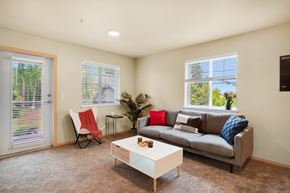 Bellingham apartment for rent - a living room with a couch and a coffee table, two windows and a glass exterior door at Sky Vue, Washington