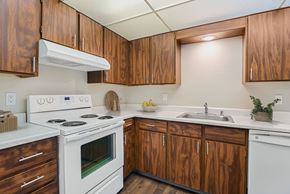 Moses Lake apartment for rent - Kitchen with warm wood cabinets, white electric range, and ample counter space at The Lakes Apartments