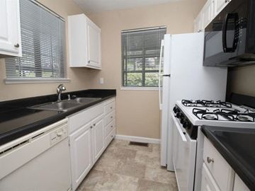 Auburn apartment for rent - A kitchen with white cabinets and black countertops.