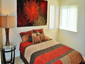 Ranch Cordova apartment for rent - A bedroom with a bed, a lamp, and a painting on the wall.