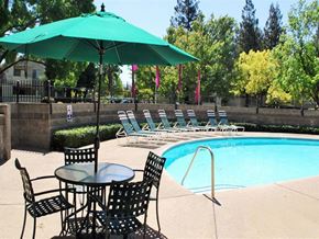 Ranch Cordova apartment for rent - A pool area with a table and chairs and a green umbrella.