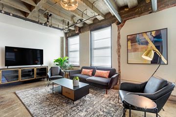 Denver apartment for rent - A living room with a black leather couch and a wooden coffee table.