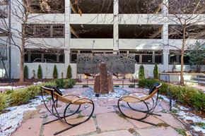 Denver apartment for rent - Courtyard Lounge with Stones, Contemporary Rocking Chairs and Contemporary  Round Swings in Front of Decorative Metal Piece in Front of Parking Garage