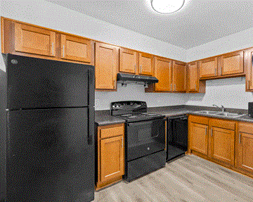 Titusville apartment for rent - A black refrigerator is in a kitchen with wooden cabinets.