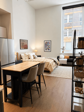 Cincinnati apartment for rent - A modern bedroom with a large bed and a wooden table.