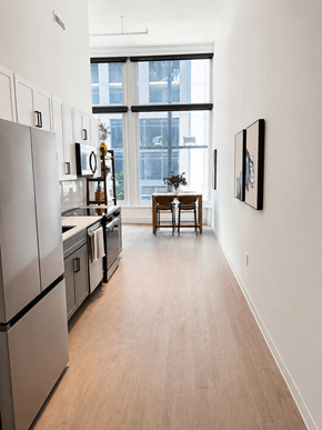 Cincinnati apartment for rent - A kitchen with a refrigerator, a dining table and chairs, and a painting on the wall.