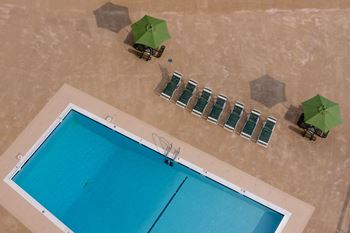 An aerial view of a swimming pool with green umbrellas and chairs