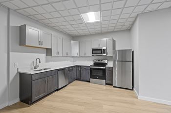 A kitchen with a refrigerator, oven, and sink.