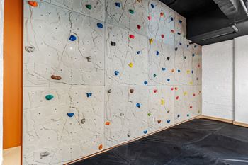 A large wall with a climbing wall with different coloredazes on it