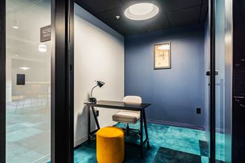 A desk with a chair and a lamp in a room with a door
