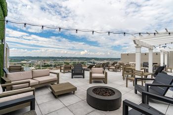 A roof top patio with couches and chairs and a fire pit