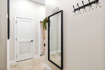 A mirror in a hallway with a closet and a door to a bathroom