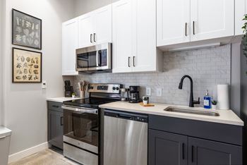 An apartment kitchen with stainless steel appliances and white cabinets